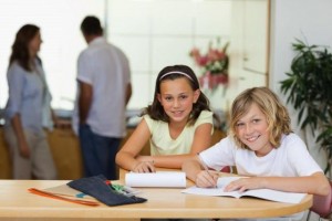 Siblings doing homework with their parents behind them